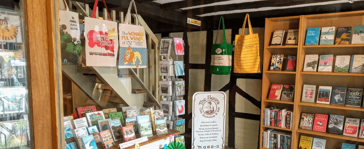 Inside the Hours Bookshop on the Usk Valley Way, with shelves of books and hanging canvas bags
